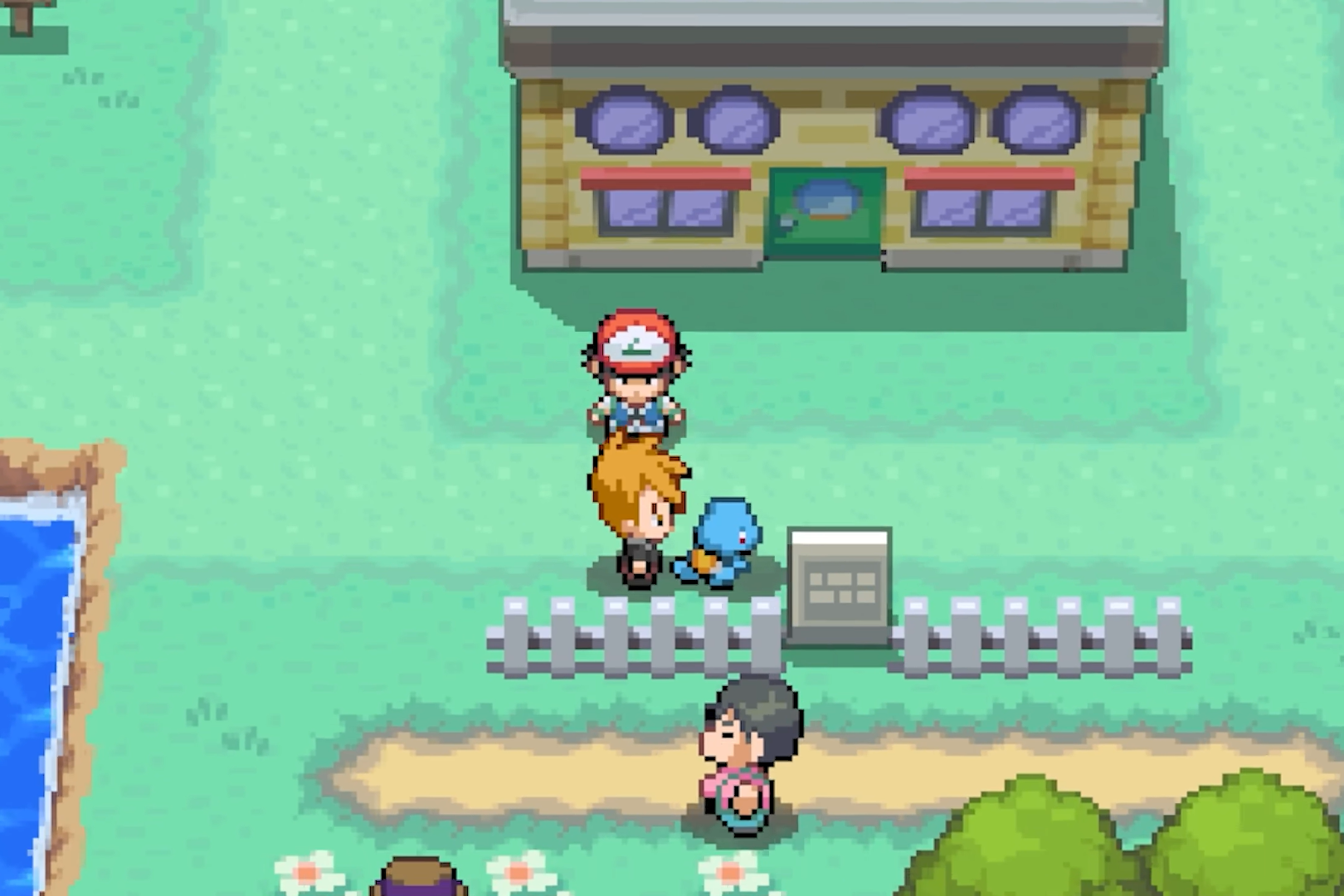 The player meets characters and Pokemon outside a town building beside a white fence.
